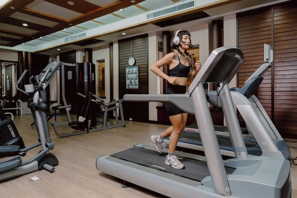 Fitnessrum på Khaolak Merlin Resort med en gæst på løbebånd, konditionsmaskiner og styrketræningsudstyr