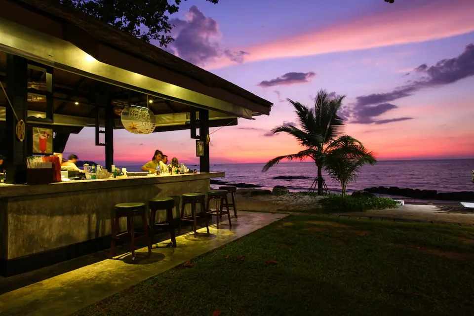 Strandbar på Khaolak Merlin Resort med barstole, palme og udsigt over havet ved solnedgang