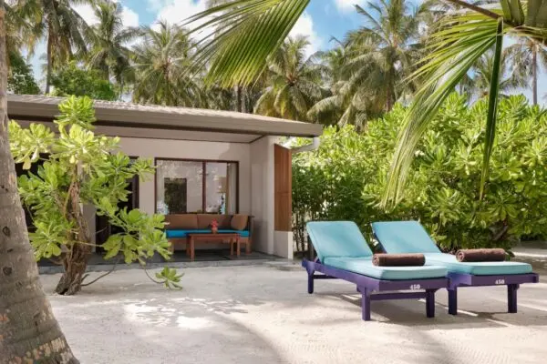 Villa med overdækket terrasse og to solstole mellem palmer på Villa Park