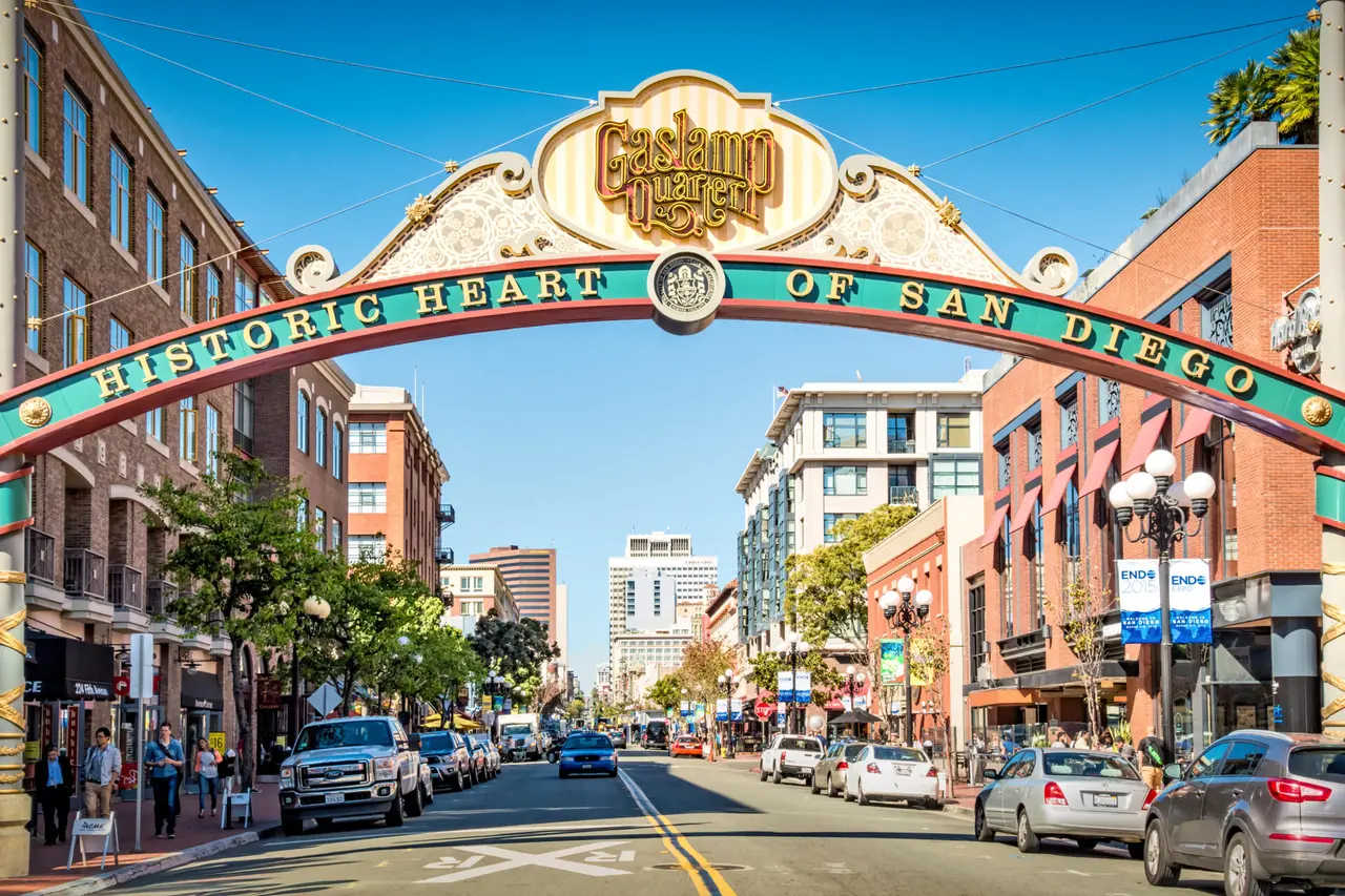 En gade med biler og fodgængere under en stor bue med teksten Gaslamp Quarter og San Diego.