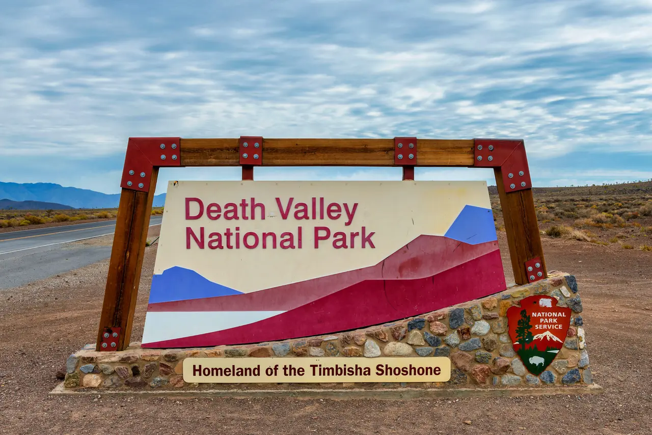 Skiltet til Death Valley National Park ved en vej gennem et tørt landskab.
