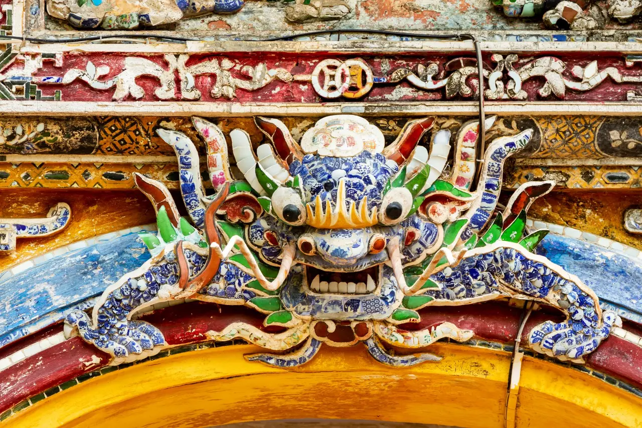 Et farverigt dragerelief med blå og hvide mosaikstykker over en gul bue.