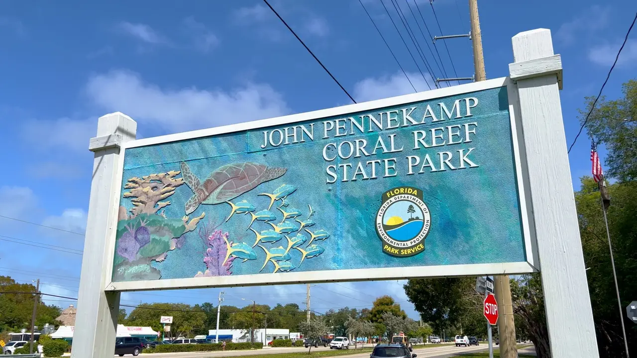 Skilt til John Pennekamp Coral Reef State Park med illustrationer af en havskildpadde og fisk.