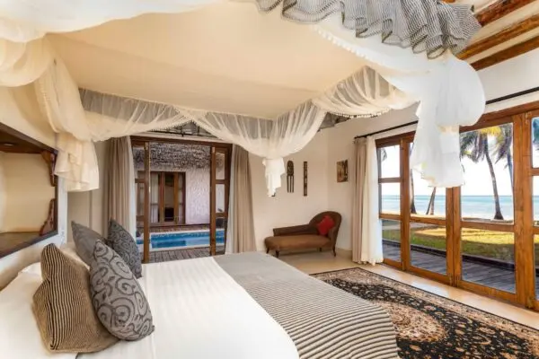 Værelse med dobbeltseng, myggenet og udsigt til pool og hav på Karafuu Beach Resort & Spa
