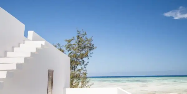 Hvid hotelbygning med udvendig trappe og udsigt over havet ved Nungwi Dreams by Mantis