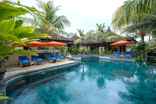 Pool og solterrasse mellem bygninger og palmer på Natya Hotel Tanah Lot