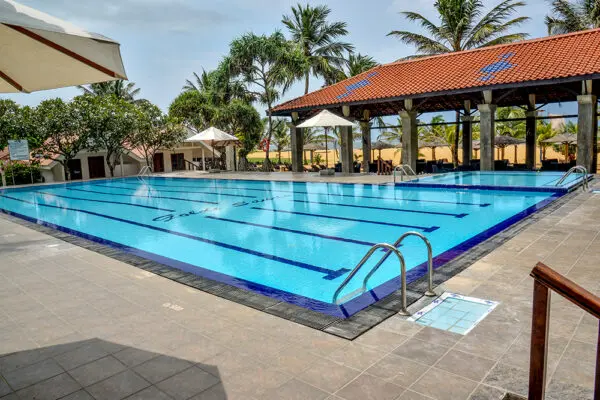 Udendørs pool med svømmebaner og palmer ved Goldi Sands Hotel