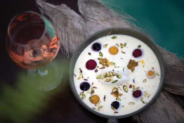 Anrettet dessert med farvede detaljer og et glas vin på Atmosphere Kanifushi