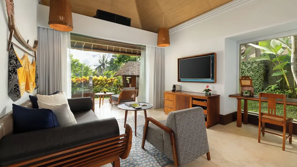 Opholdsrum med sofa, lænestol og adgang til terrasse på Maya Ubud Resort & Spa