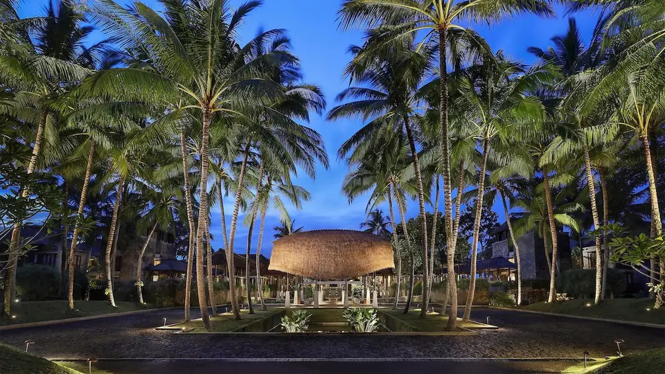 Belyst pavillon og palmer ved resortets indgang på Maya Ubud Resort & Spa