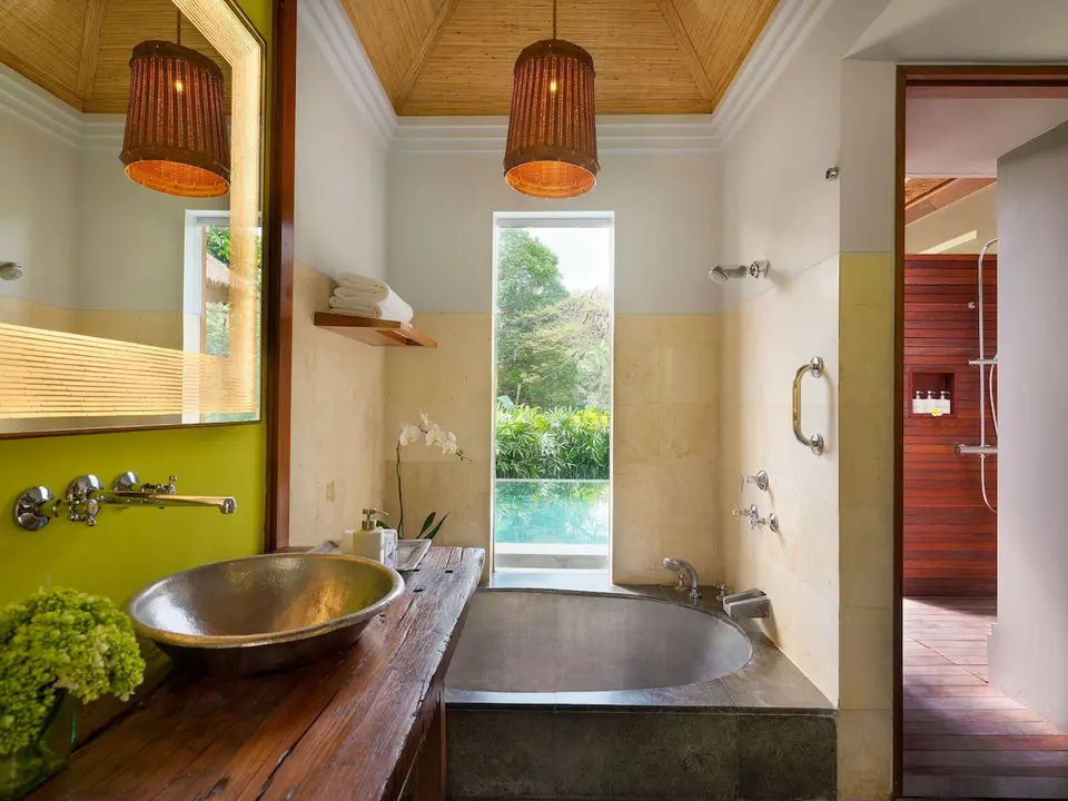 Badeværelse med badekar og håndvask på træbord på Maya Ubud Resort & Spa