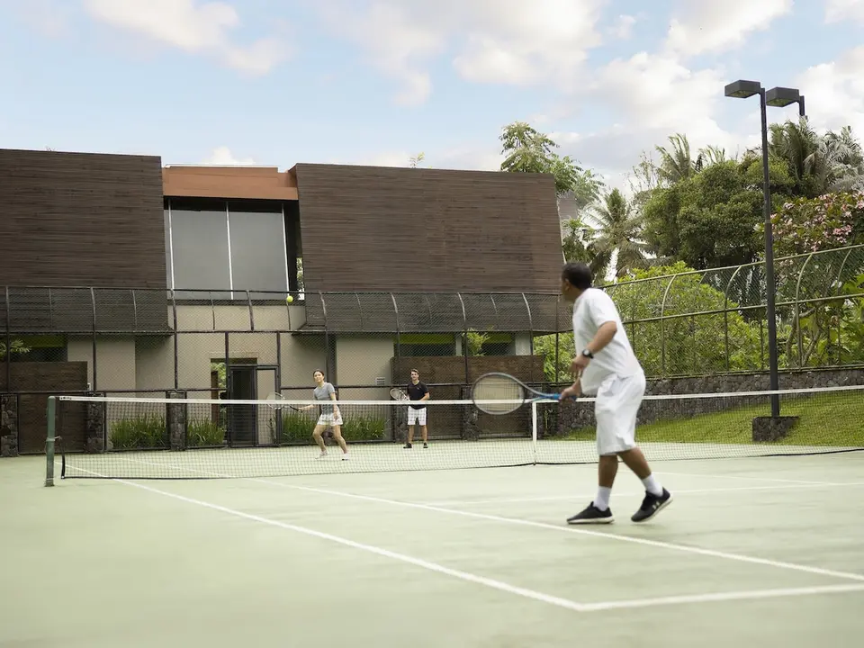 Tennisbane med spillere og grønne omgivelser på Maya Ubud Resort & Spa