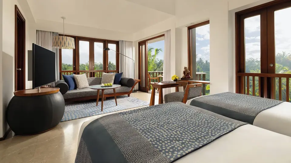 Værelse med to senge og sofa ved store vinduer på Maya Ubud Resort & Spa
