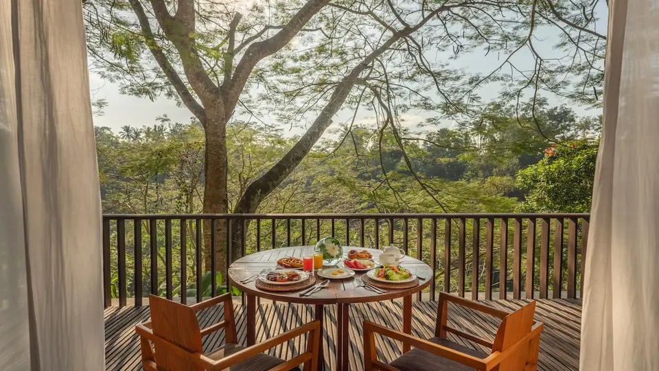 Balkon med bord, stole og udsigt til træerne på Maya Ubud Resort & Spa
