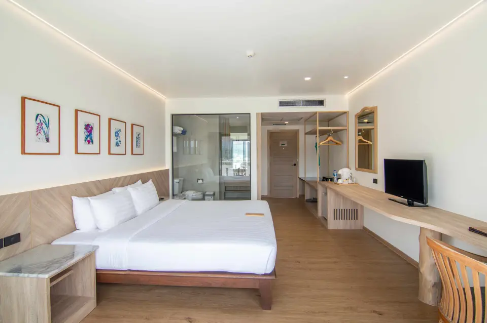 Værelse med dobbeltseng, tv, skrivebord og glasvæg mod badeværelset på Orchidacea Resort