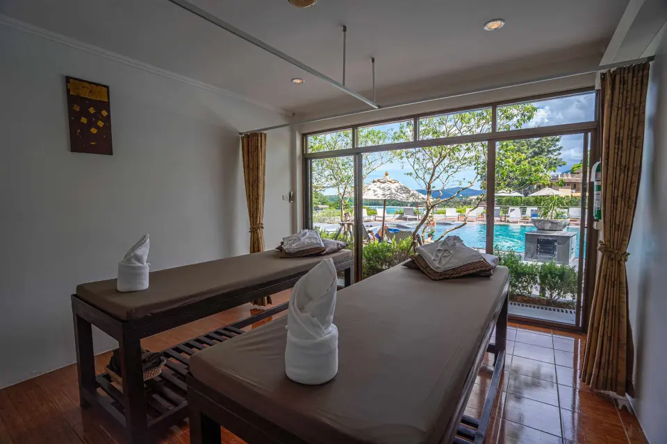 Massagerum med to massagebrikse og store vinduer mod poolområdet på Orchidacea Resort