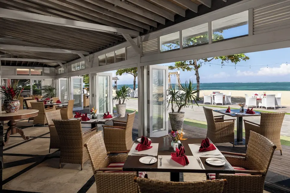 Restaurant med dækkede borde og åben udsigt mod stranden