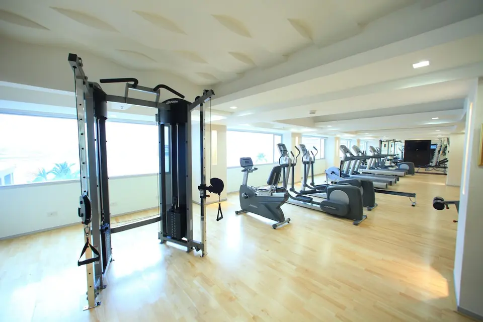 Fitnessrum med træningsmaskiner, motionscykler og store vinduer
