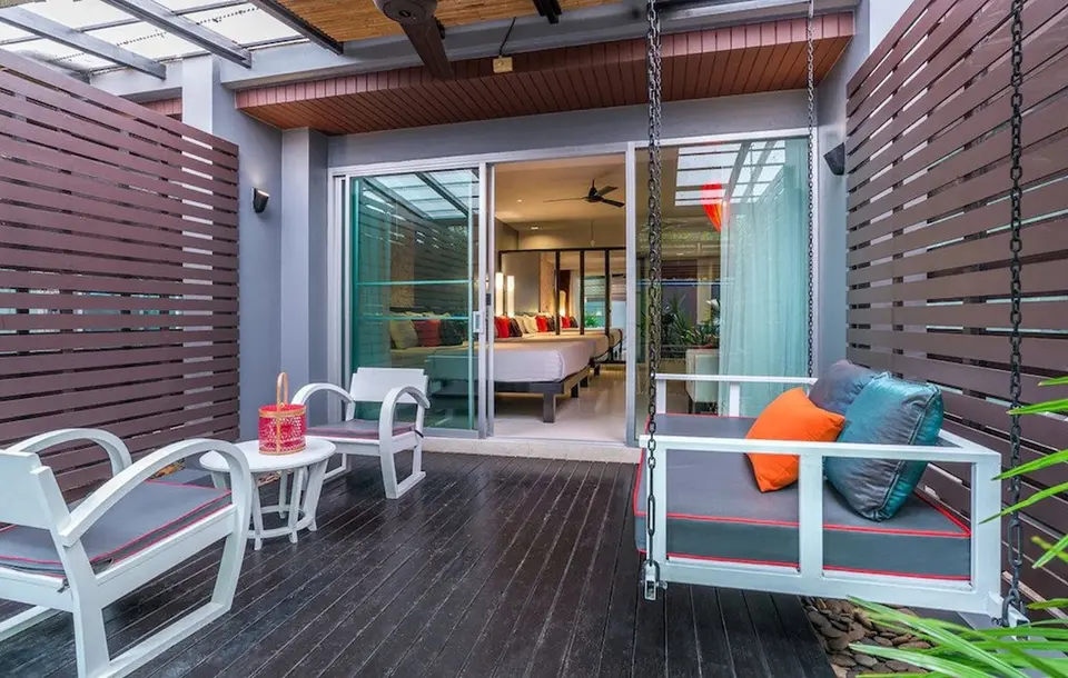 Overdækket terrasse med hængesofa og stole foran et værelse på Red Ginger Chic Resort