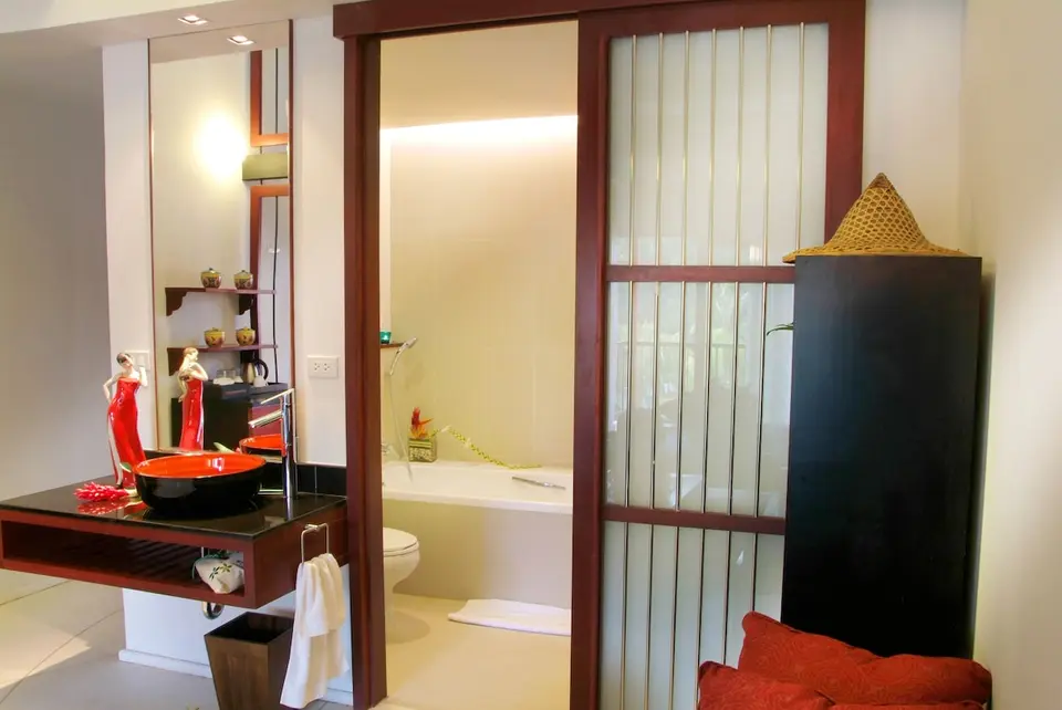 Badeværelse med rød håndvask, spejl og badekar på Red Ginger Chic Resort