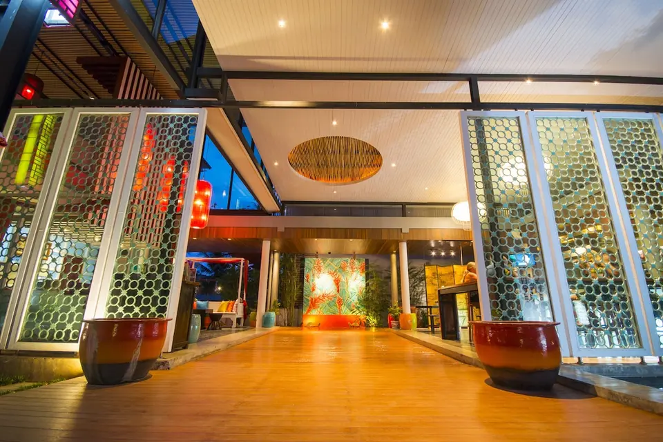 Indgang til lobbyen med trægulv og mønstrede skærme på Red Ginger Chic Resort