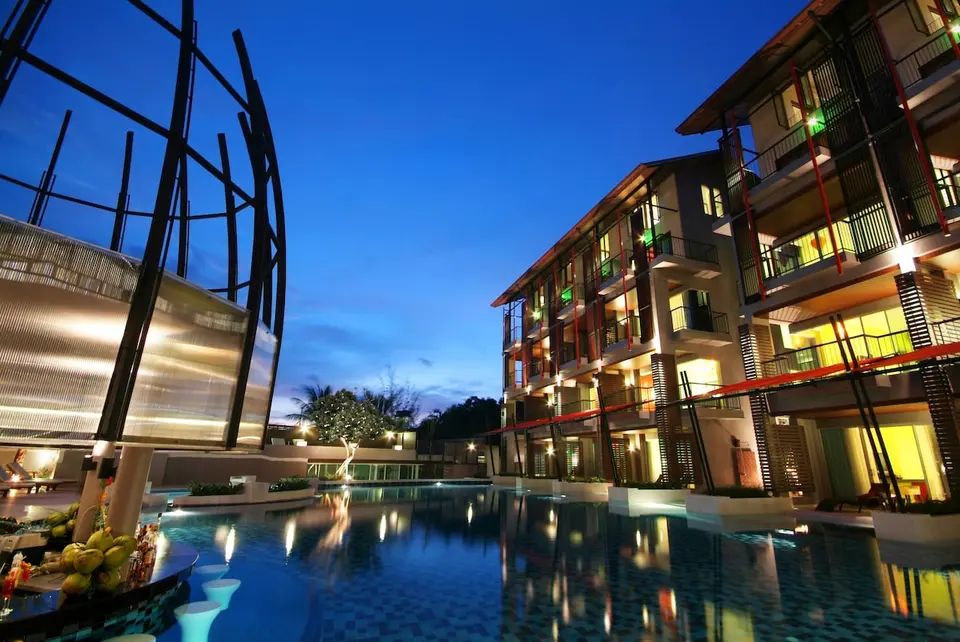 Pool og oplyste værelsesbygninger i skumringen på Red Ginger Chic Resort