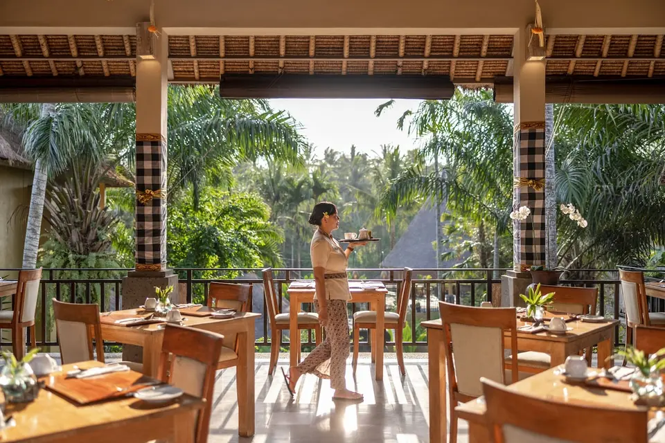 Restaurant med træborde og åben udsigt til palmer hos The Sankara Resort & Spa.