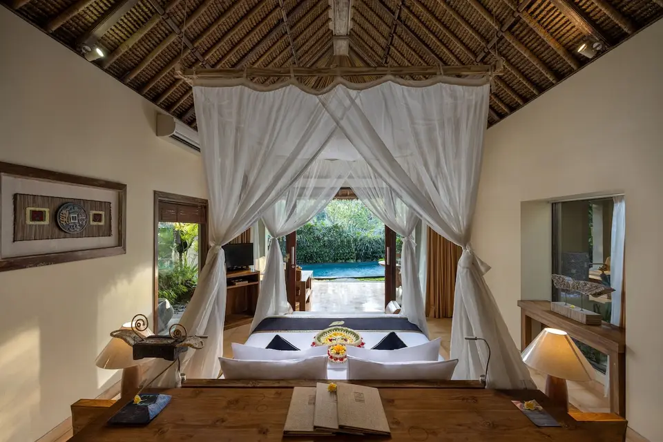 Værelse med himmelseng, træloft og åbning mod pool hos The Sankara Resort & Spa.
