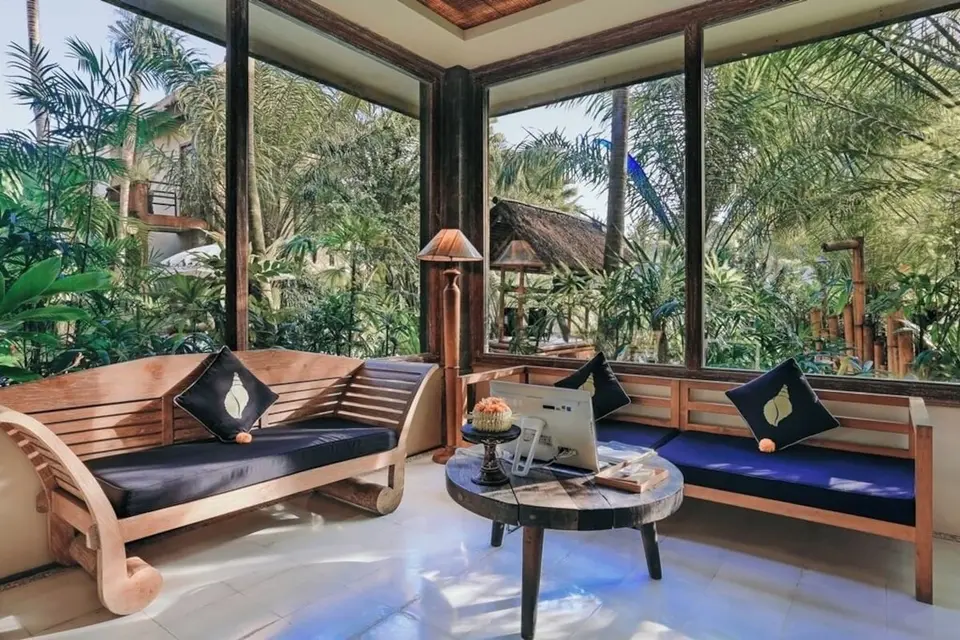 Opholdsområde med træsofaer og store vinduer mod haven hos The Sankara Resort & Spa.
