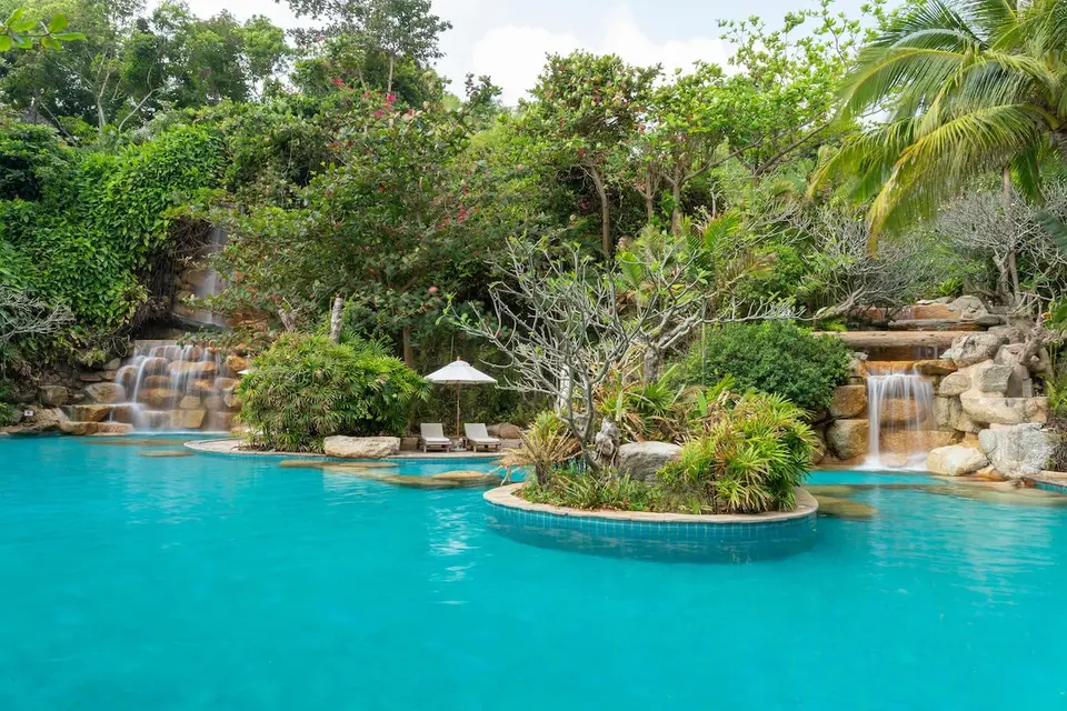 Santhiya Koh Phangan: Pool med vandfald, klipper og tæt grøn beplantning.