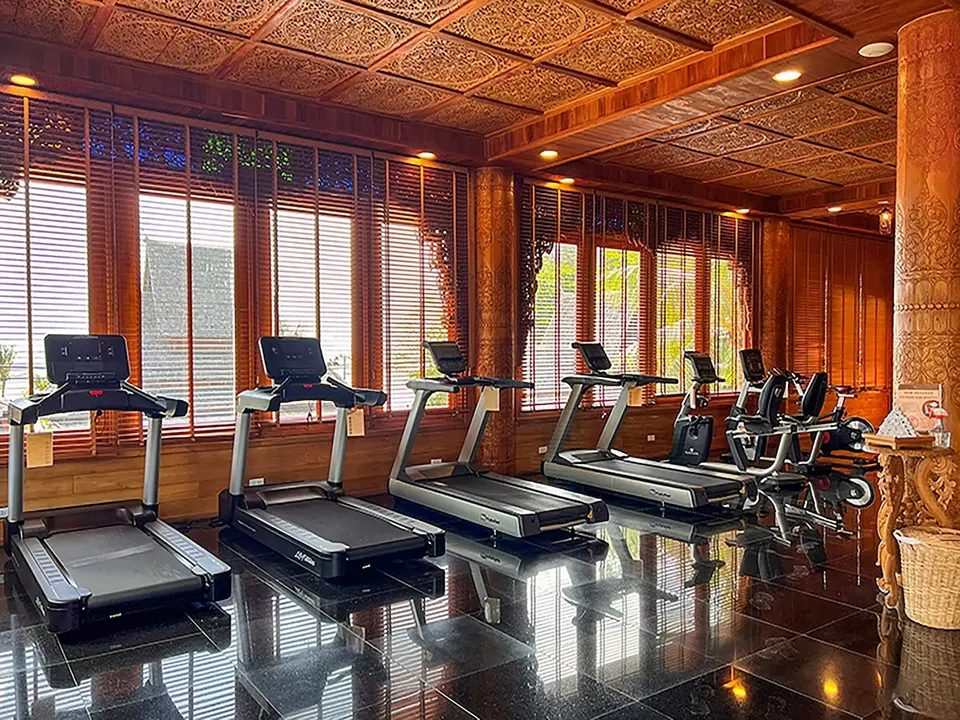 Santhiya Phuket Natai: Fitnessrum med løbebånd, motionscykler og udskåret træloft.
