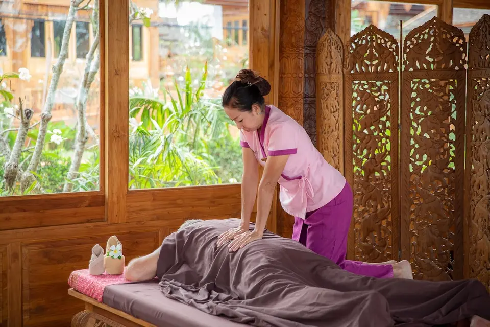 Santhiya Phuket Natai: Massage i et behandlingsrum med træpaneler og udsigt til haven.
