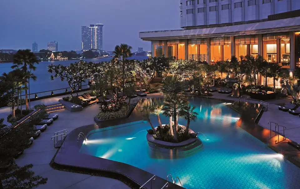 Shangri-La Bangkoks oplyste poolområde med udsigt over Chao Phraya om aftenen