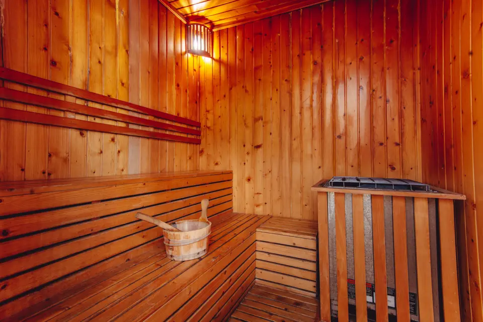 Sauna med træbænke, træspand og saunaovn.