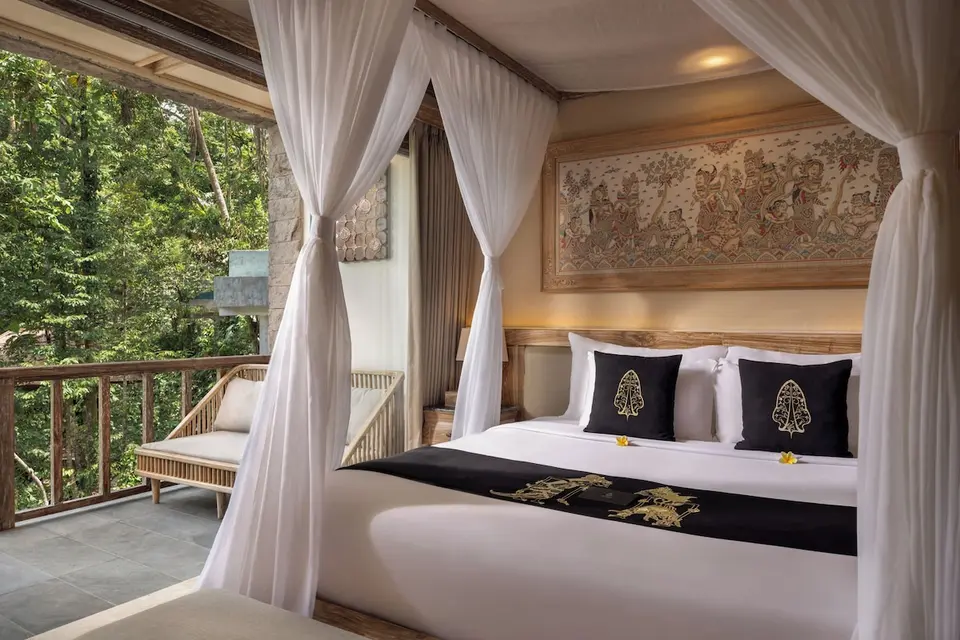 Soveværelse med himmelseng og balkon på The Kayon Resort