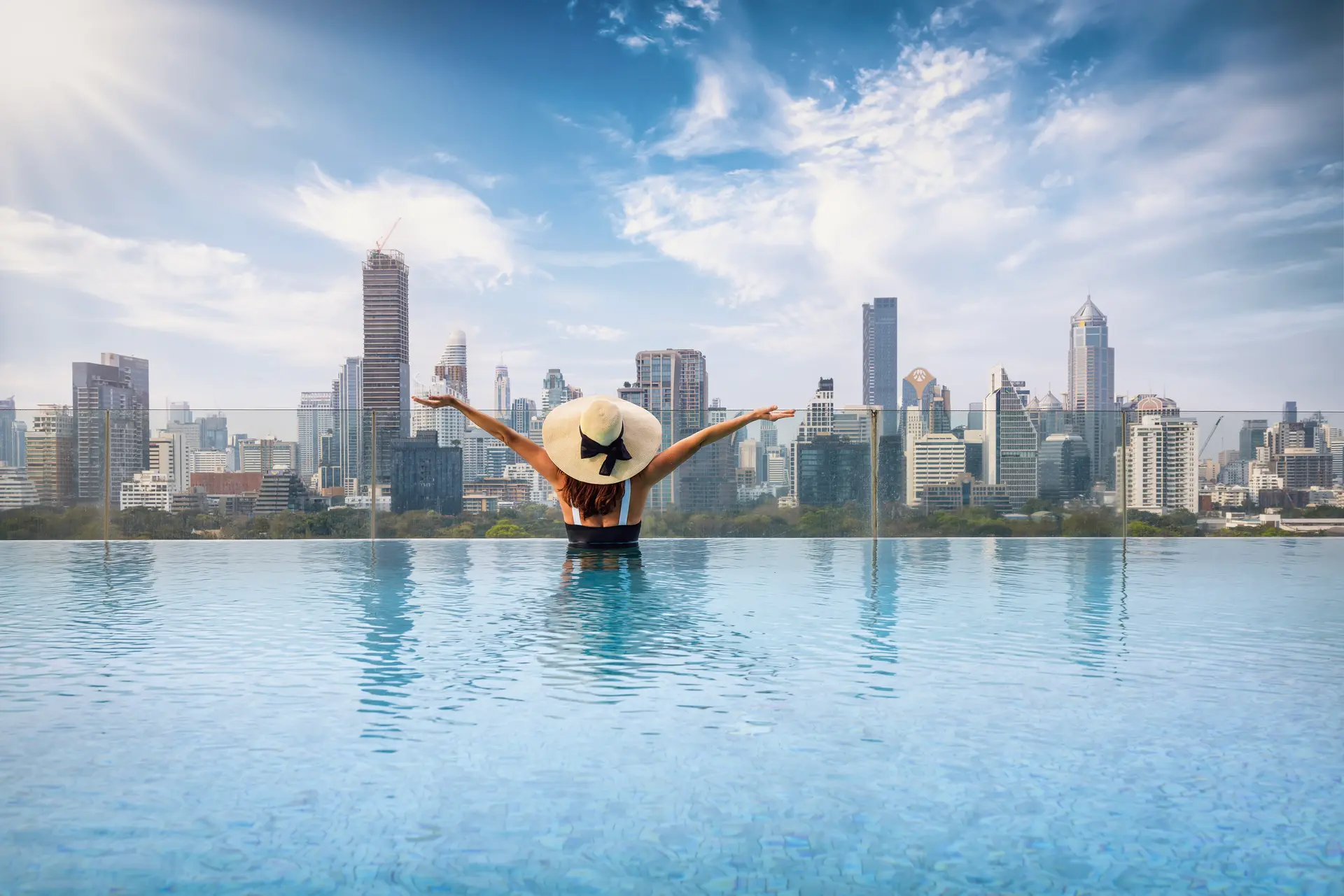 Kvinde i pool nyder udsigten over bangkok skyline