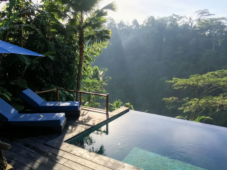 Poolterrasse med liggestole og udsigt til dalen på Ubud Valley Boutique Resort