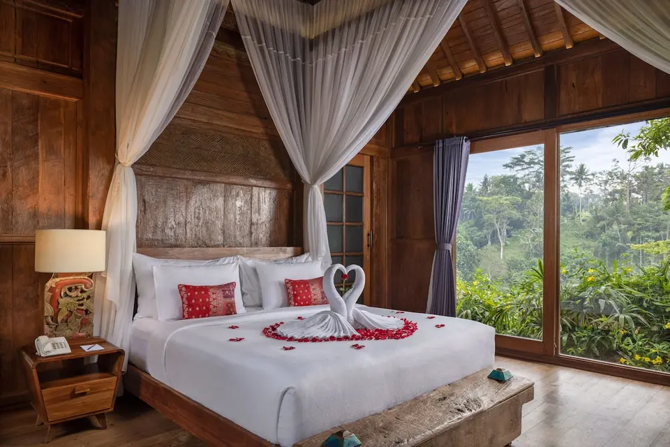 Soveværelse med himmelseng og store vinduer på Ubud Valley Boutique Resort
