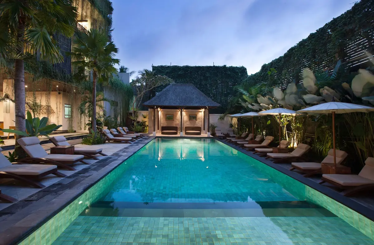 Pool med solsenge og parasoller på Ubud Village Hotel