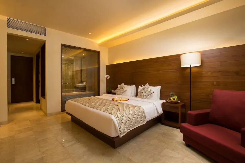 Værelse med dobbeltseng og rød lænestol på Ubud Village Hotel