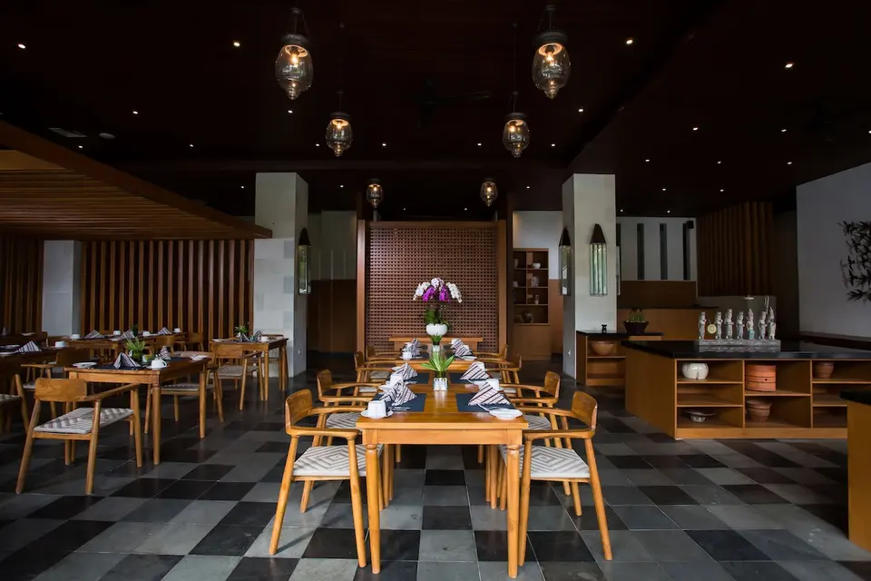 Restaurant med træmøbler og ternet gulv på Ubud Village Hotel
