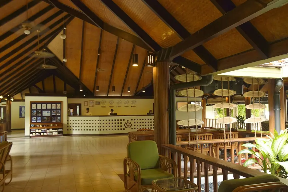 Reception og opholdsområde på Villa Nautica med højt træloft, skranke og grønne lænestole