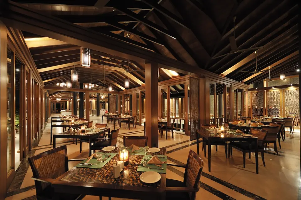 Restaurant på Villa Nautica med dækkede borde, levende lys og synlige træbjælker om aftenen