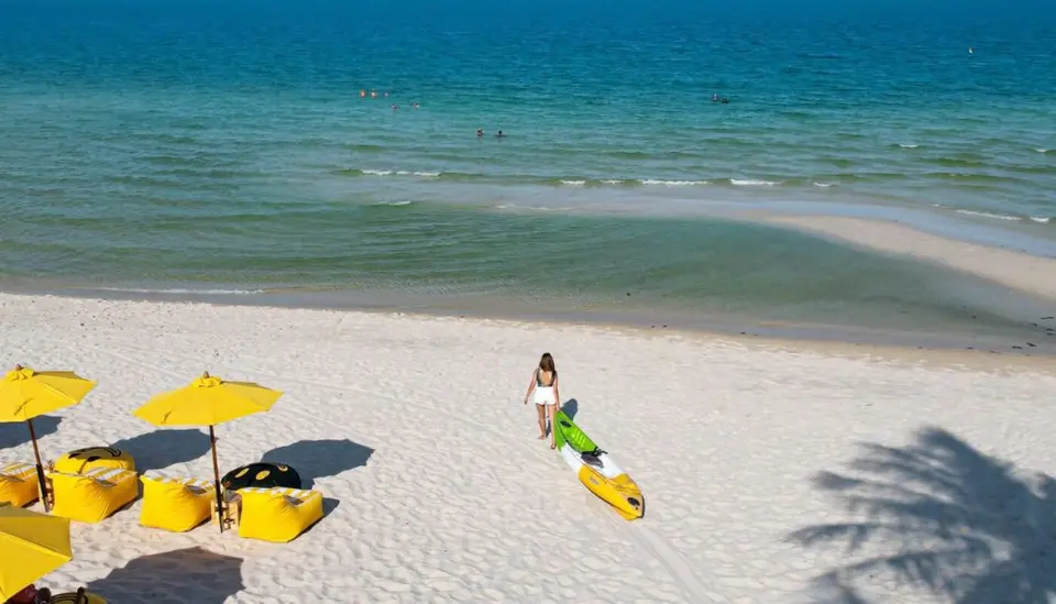 Strand med gule parasoller og en gæst med kajak ved Banana Fan Sea Resort.