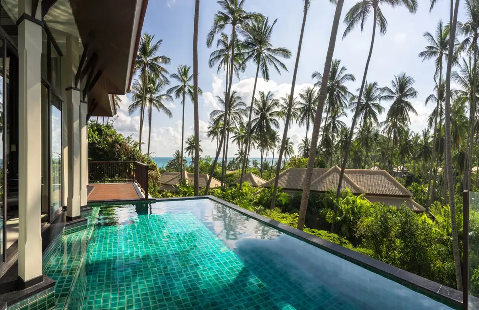 Oplev Banyan Tree Samui's pool med udsigt til havet og palmetræer.
