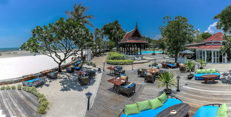 Restaurantterrasse med borde, siddepladser og pavillon ved stranden.