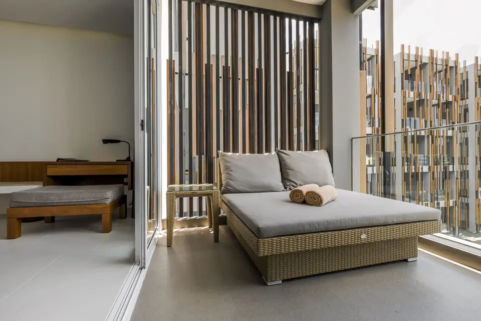 Daybed på overdækket balkon med glasgelænder.