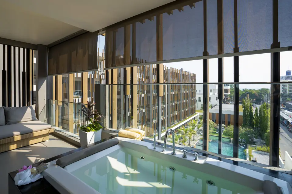 Boblebad og daybed på balkon med udsigt til hotelbygningen.