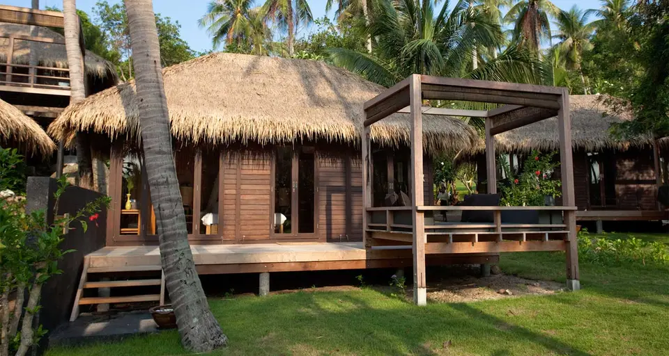 Stråtækt bungalow med træterrasse og overdækket daybed.