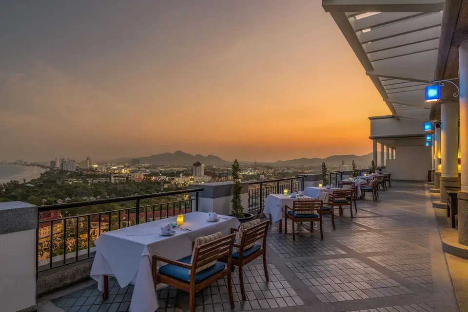 Restaurantterrasse med udsigt over byen i aftenlys.